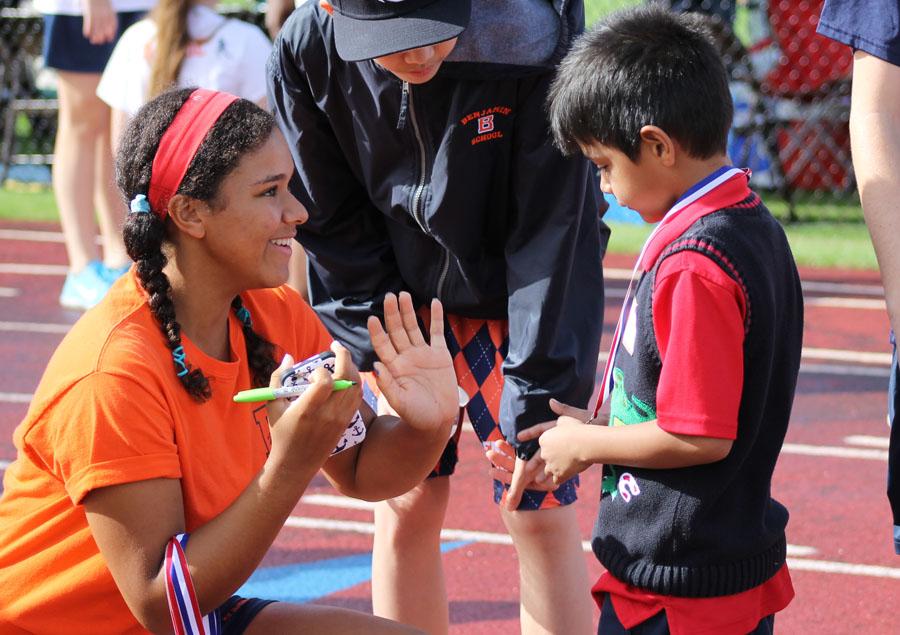 Eighth graders Hannah Foster (left) and Shayne Mao congratulate a young competitor during the Games.