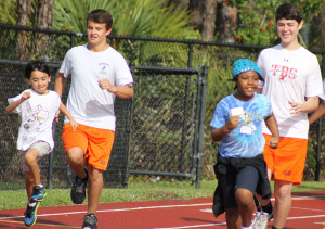 George Matthews (left) and Ben Chait run down the track with some of the elementary school participants.