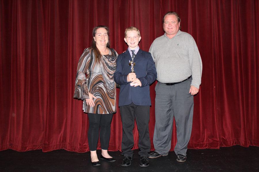 Royce+Howley%2C+holding+his+trophy%2C+stands+with+his+parents+after+winning+the+middle+school+spelling+bee.