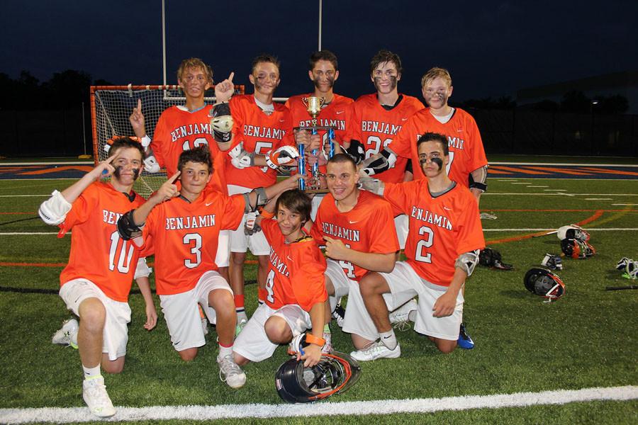 The boys lacrosse team celebrates its championship with the trophy at the Upper School.