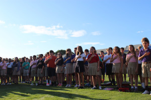 Middle School students place their hands over their hearts in reciting "The Pledge of Allegiance" to begin Friday's ceremony. The U.S. flag was lowered to half-mast throughout the day.