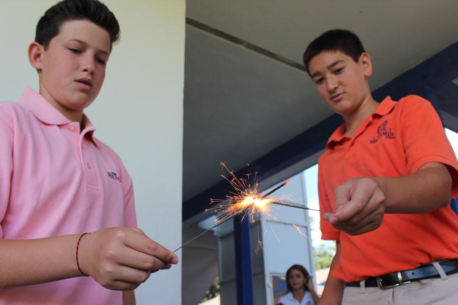 Eighth grader Joey Berg (left) carefully lights the sparkler of classmate James Richardson outside the Buc Café on August 18, 2015.