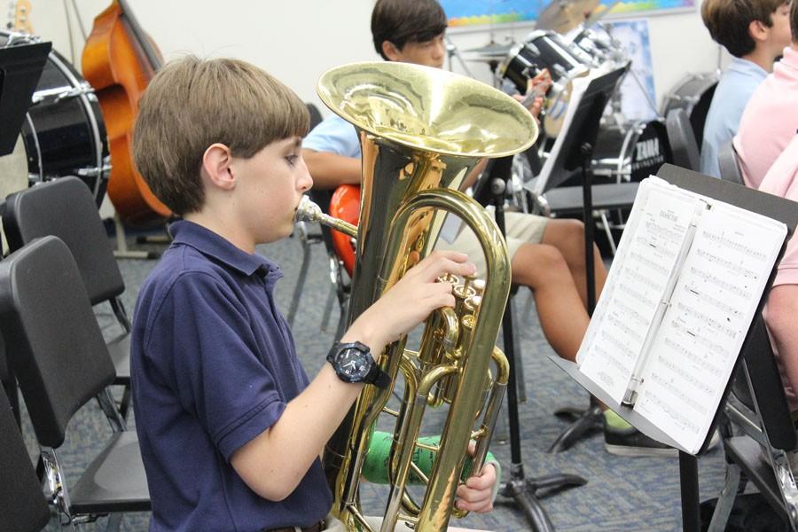 Despite his broken arm (see the green cast?), Mitch is poised to play his best at the All-State Band Concert in January. Here he practices the euphonium during his band class at TBS.