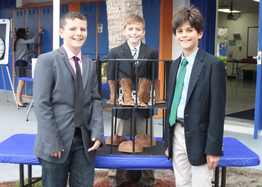 Left to right: Sixth graders Zachary Loceff, Casey Crawford, and Jake Zur pose with their Heritage Day project which they created with the help of artists from the Center for Creative Education. Their project includes molds of faces and chained feet, meant to represent the slaves that were brought over to the colonies from Africa.