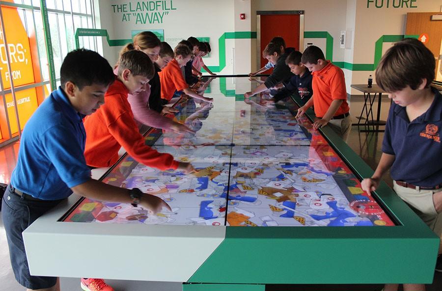 The sixth graders play the recycle game on the giant interactive table at the SWA facility.