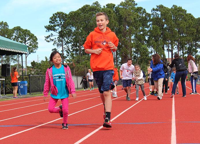 Eighth grader Christian Cassanelli runs alongside one of the elementary school participants during the 100-yard dash. 