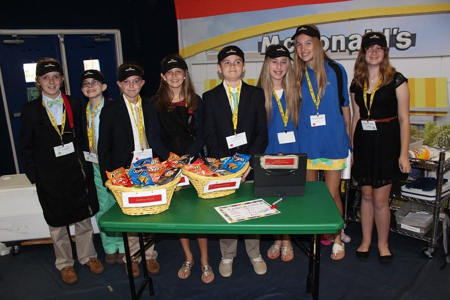 Left to right: Tate Ford, Jakob Kroll, James Key, Emeline Smith, Louis Gaeta, Sydney Steinger, Ecdn Josza, and Lucy Campbell pose in front of their McDonalds store sign in BizTown during Career Day.