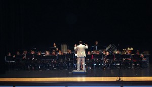 The Middle School Performance Ensemble Band plays on stage under the direction of Mr. Huber.