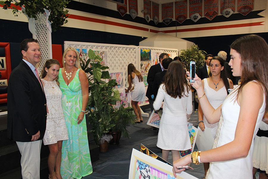Eighth grader Emma Johnson (right) photographs fellow classmates Caroline Charles and Charles' parents at the end of the evening.