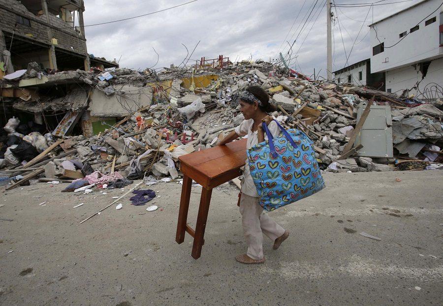 A woman carries a table through the street after an earthquake in Pedernales, Ecuador, Sunday, April 17, 2016. 