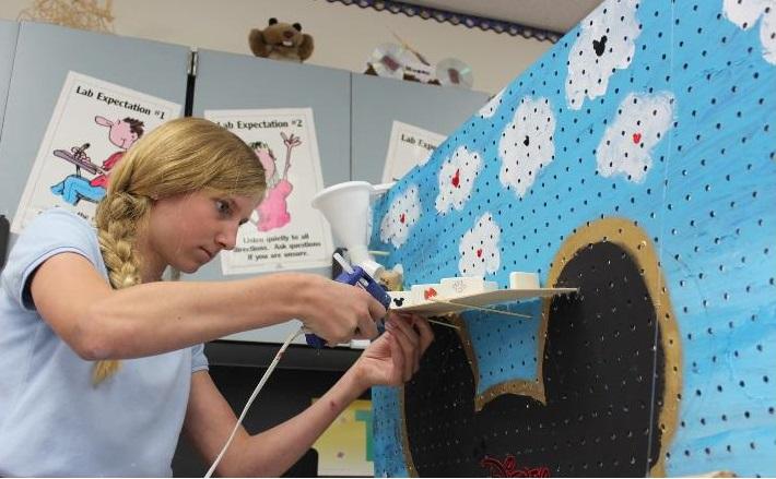 Eighth+grader+Regan+Kretz+uses+a+glue+gun+to+affix+some+components+to+her+Disney-themed+Rube+Goldberg+project.