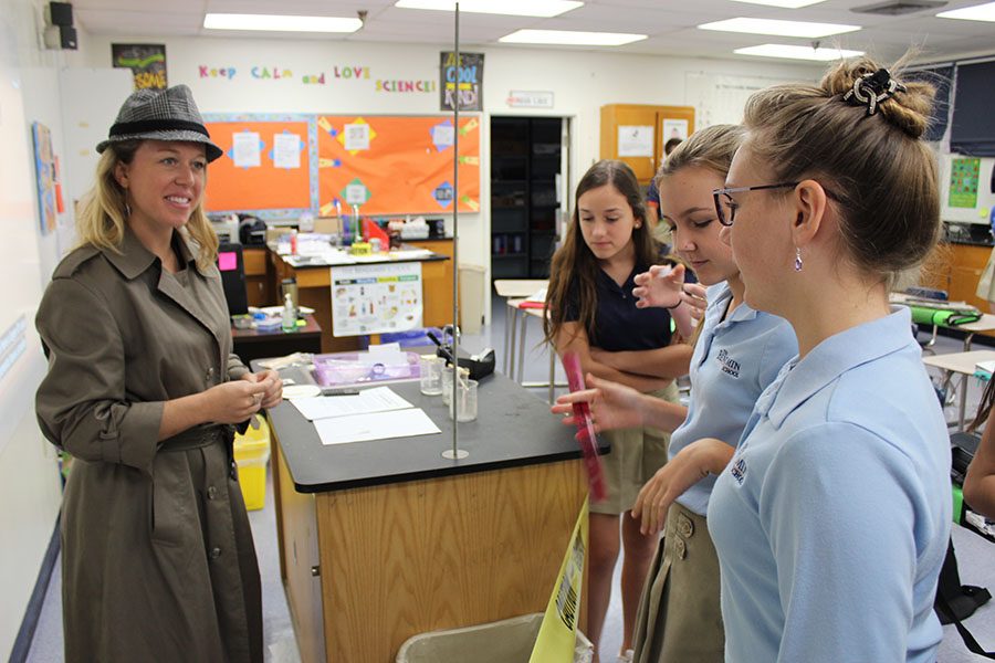 Detective Holmes (Featherston) discusses the case with eighth graders (left to right) Kayla Schneider, Nadia Poncy, and Briley Crisafi.