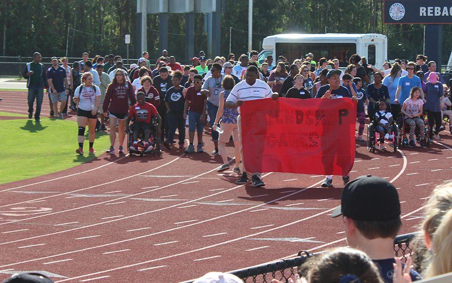 The students who participated in the Friendship Games carry a banner around Reback to kick off the day.