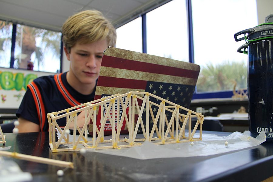 With his bridge in the foreground, eighth grader Carter Stewart conducts research on different types of truss bridges.