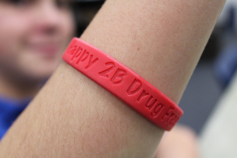 Eighth+grader+Caden+Quinn+displays+the+rubber+bracelets+that+were+given+to+students+during+Red+Ribbon+Week.+Each+one+read%2C+Happy+2B+Drug+Free.