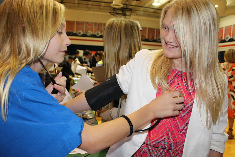 Sixth grader Emma Nordland (left), working as a health and wellness employee, listens to the heartbeat of fellow classmate Winni Cox during their time in BizTown on Friday, December 1.