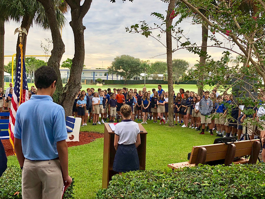 Seventh grader Emerson Ferry reads a portion of President Donald Trumps Patriot Day proclamation to the Middle School in the quad on September 11, 2018.