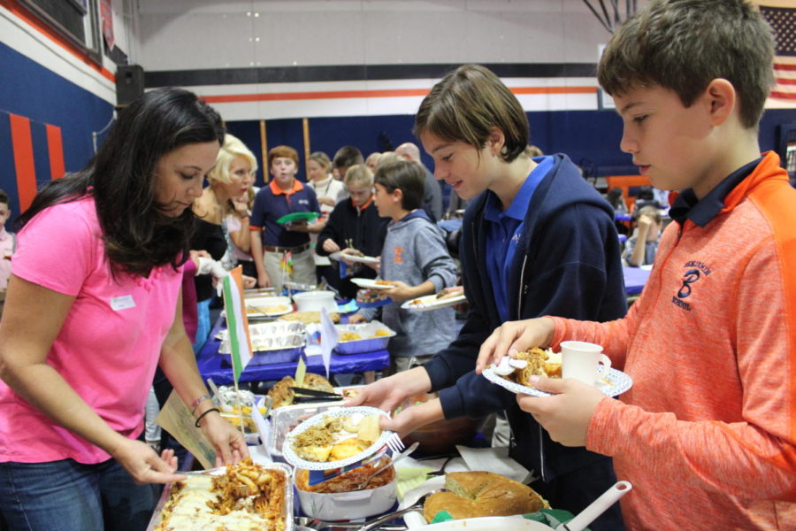 Sixth graders Sofie Odehnalova and Kian Interlandi are served a variety of different foods by parents during the Heritage Day feast.