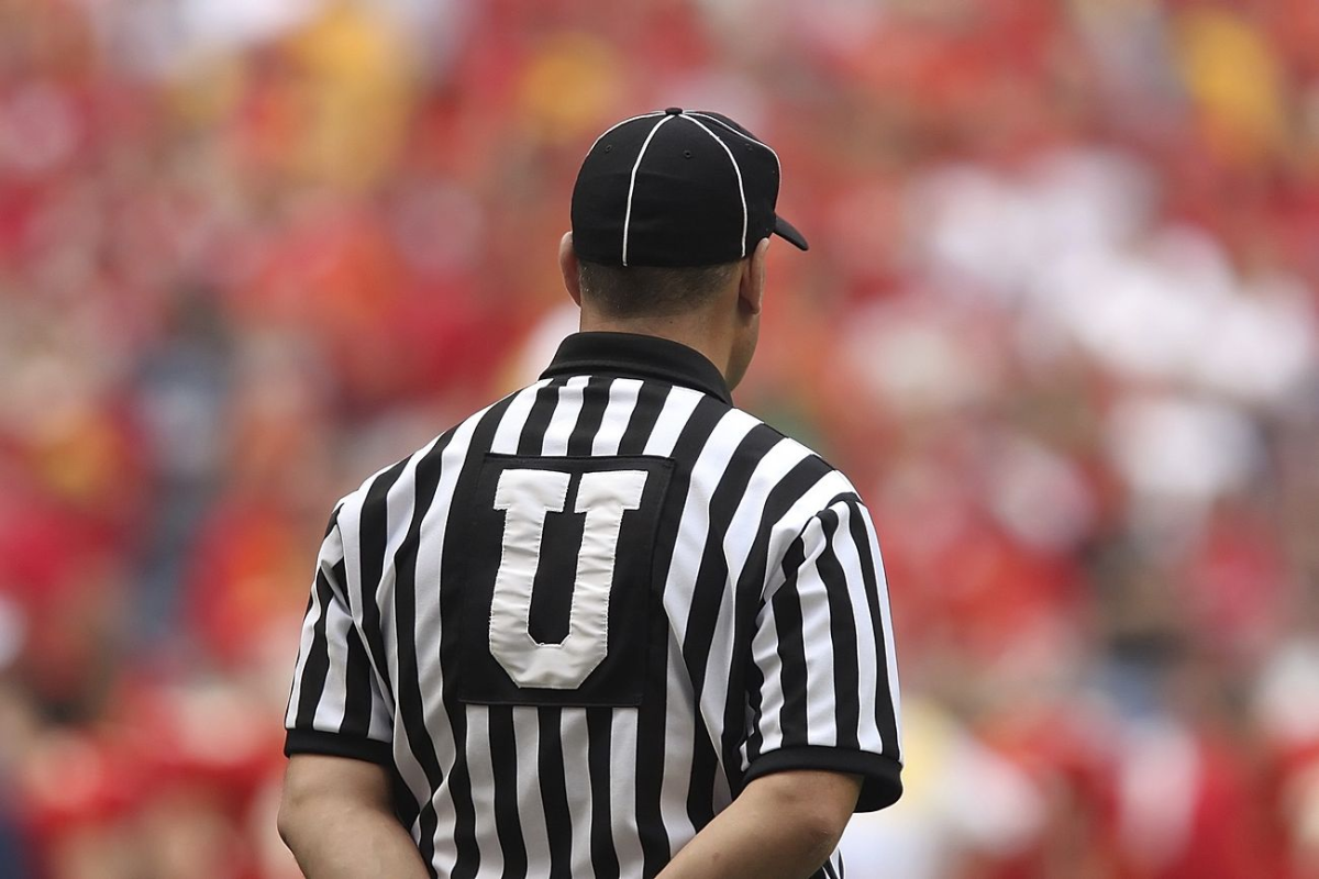 A NCAA referee is awaiting the start of a bowl game