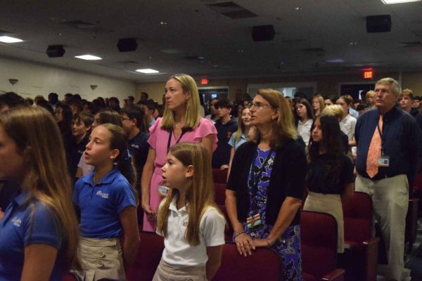 New 6th graders and teachers rise for the pledge at the morning assembly